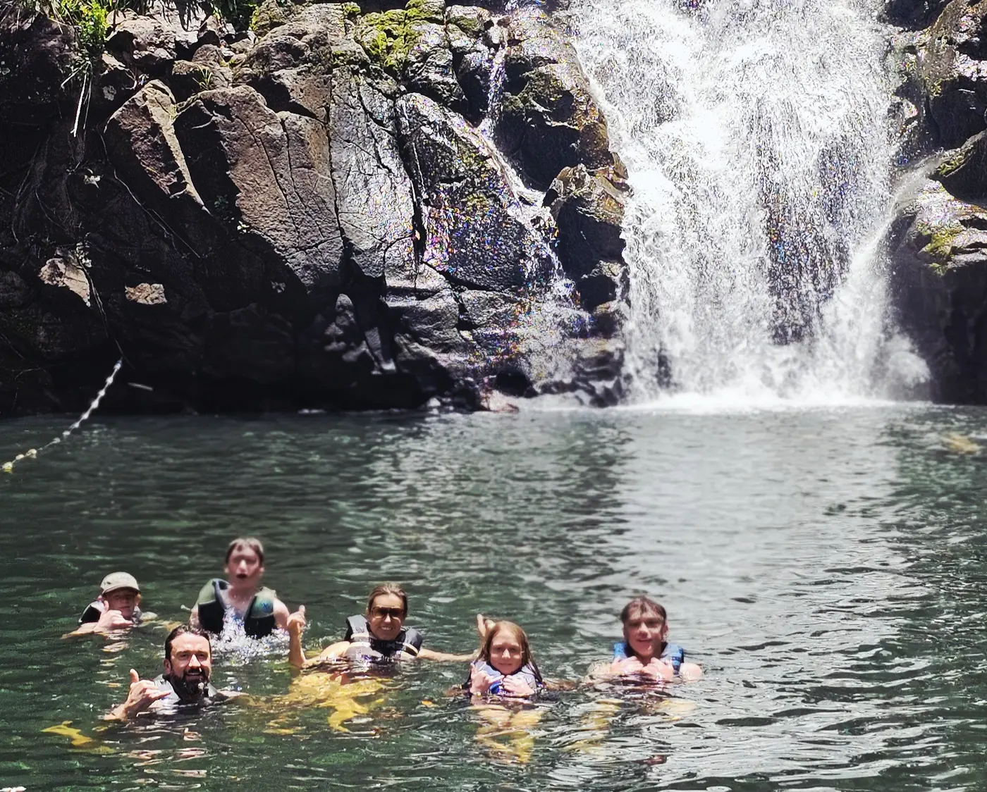 A family enjoying the waterfall pool at Waimea Valley