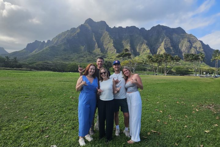 Family posing together with green Oʻahu mountains behind them