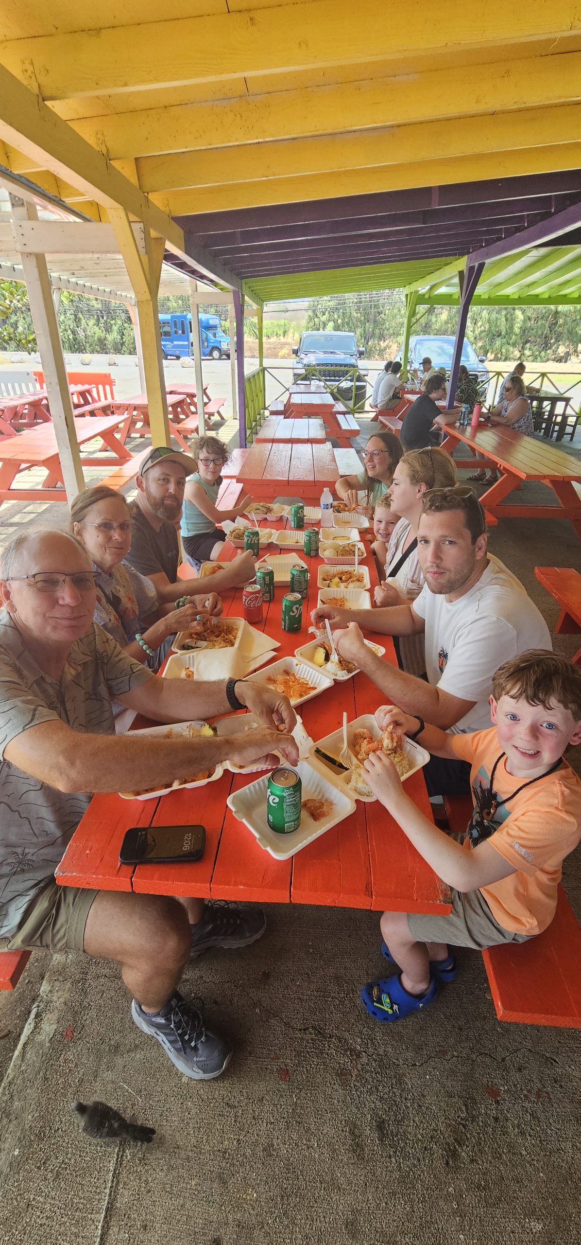 Family sharing lunch at a picnic table under covered outdoor seating